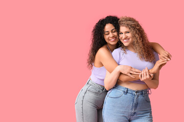 Beautiful young women hugging on pink background