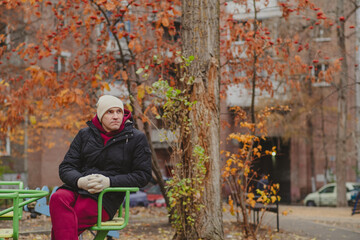 Man sitting pensively on a colorful carousel in an autumn park, contemplating life in a quiet moment