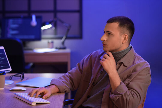 Male programmer working with computer in office at night