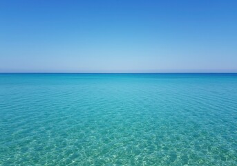 Obraz premium Serene turquoise ocean water with sun rays reflecting on the surface, clear blue sky background, perfect for summer vacation advertising, travel and relaxation concept