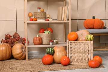 Shelving unit with wicker basket of different pumpkins near beige wall