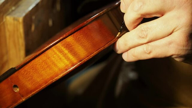Close up of maker carefully varnishing violin ribs using brush with self made varnish, highlighting the craftsmanship and precision involved in creating stringed instruments, slow motion shot - Powered by Adobe