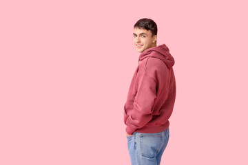Handsome young man in stylish hoodie on pink background