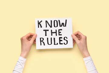Woman holding paper with text KNOW THE RULES on beige background