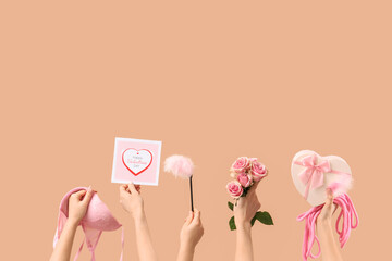 Female hands with sex toys, roses, card and bra on beige background. Valentine's Day celebration