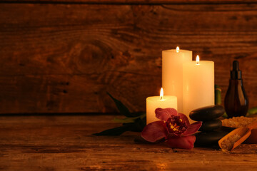 Spa composition with burning candles and orchid flower on dark wooden table