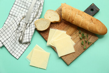 Board with slices of tasty processed cheese, bread and napkin on turquoise background. Top view