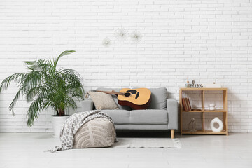 Modern acoustic guitar on grey sofa in stylish living room