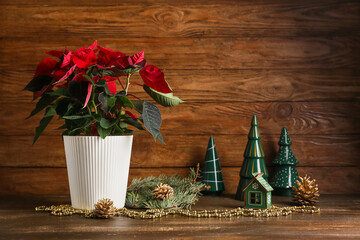 Beautiful Christmas plant poinsettia, decorations and fir branches on wooden background