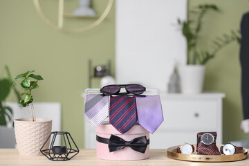 Box with men's neckties, sunglasses and bow on table in boutique