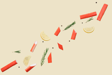 Cut tasty crab sticks with rosemary, peppercorns and slices of lemon flying on green background © Pixel-Shot
