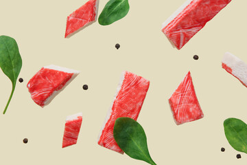 Cut tasty crab sticks with peppercorns and spinach leaves flying on green background © Pixel-Shot