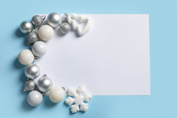 Silver Christmas baubles with blank greeting card on blue background