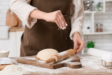 Fototapeta premium Woman rolling out fresh dough in kitchen