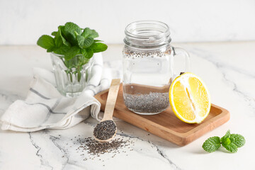 Mason jar of water with chia seeds, mint and lemon on white grunge background
