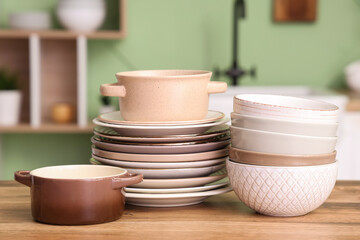 Clean plates and bowls on wooden counter in kitchen, closeup