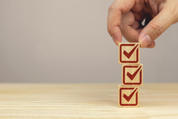 Hand picks up a stack of wooden blocks with check icons. checklist survey concept, and evaluation...
