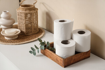 Wooden tray and rolls of toilet paper on table in bathroom