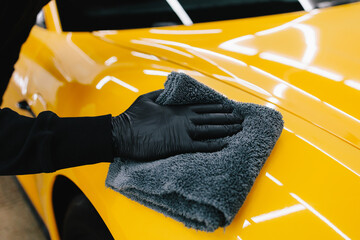 Cleaner worker dry body car using microfiber after washing automobile. Hand car drying with...