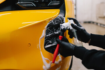Car detailing procedure at the car wash. Cleaner washes air system with soap foam using brush.