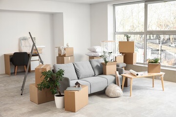 Sofa and table with cardboard boxes in room on moving day