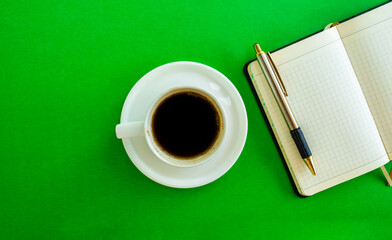 Desktop. Notepad, pen and coffee cup on green background, top view.