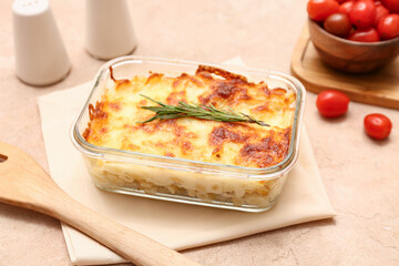 Baking dish with tasty pasta, cheese and rosemary on beige grunge background