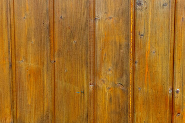 Rustic wooden wall of a cabin showcasing the natural grain and texture of the timber in vibrant tones