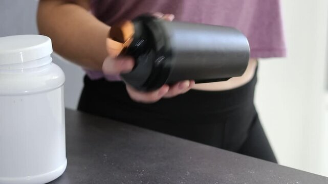 Close up of a woman preparing a protein shake in a black shaker bottle. Diet meal replacement for weight loss