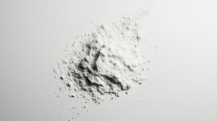 Fototapeta premium Loose powder spilling onto a clean white surface, forming a soft, natural texture. The minimalist composition highlights the fine particles and subtle shadows.