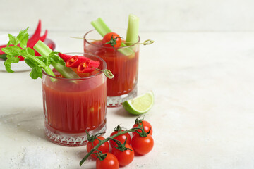 Glasses of bloody mary cocktail with chili pepper, celery and lime on white background