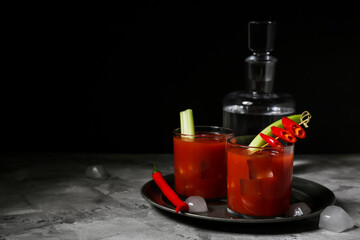 Glasses of bloody mary cocktail with chili pepper and celery on grey table