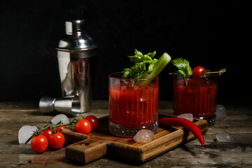 Glasses of bloody mary cocktail with celery and chili pepper on wooden table