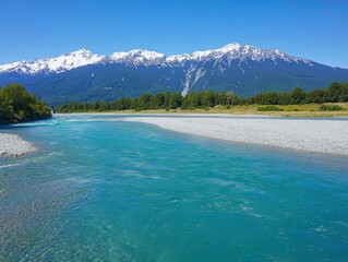 Fototapeta premium Scenic River Flowing Below Snow-capped Mountains on a Clear Day