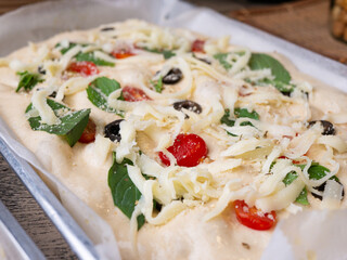 Raw Focaccia with olive tomatoes and rosemary. Homemade Italian Sourdough Bread on white cafe table.