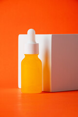 Plastic yellow tube for cream or lotion. Skin care or sunscreen cosmetic with stylish props on orange background.