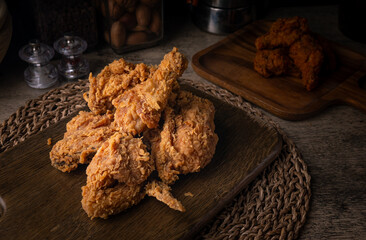 Crispy Fried chicken on a wooden plate Set on dark dinning table.