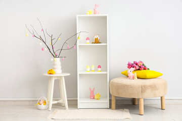 Interior of festive living room with shelving unit, pouf, bunnies and painted eggs. Easter celebration