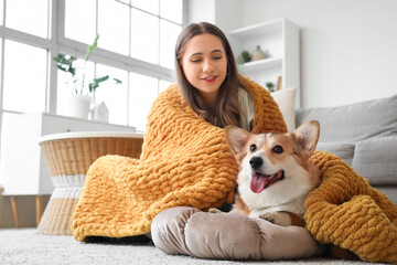 Young woman and Corgi dog with orange plaid on floor at home