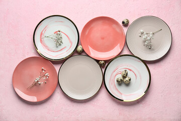 Different clean plates with quail eggs and beautiful gypsophila flowers on light pink background....