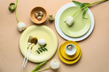 Different clean plates with Easter eggs, toy bunny and beautiful tulip flowers on beige background