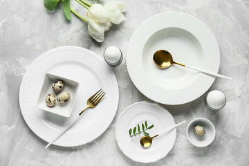 Different clean plates with Easter eggs and beautiful tulip flowers on grey background