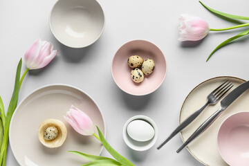 Different clean plates with Easter eggs and beautiful tulip flowers on grey background