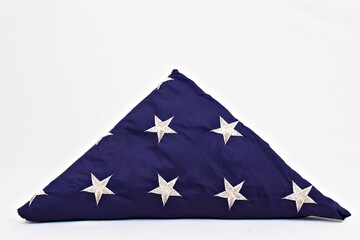 A United States flag folded into a triangle with the stars showing. On a white background.
