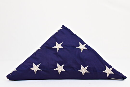 A United States flag folded into a triangle with the stars showing. On a white background.
