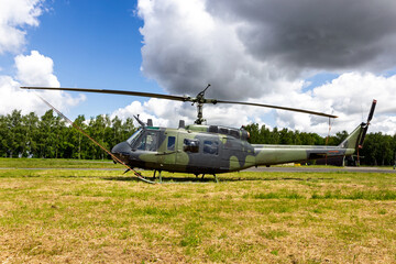 Green camouflaged army helicopter parked on the grass