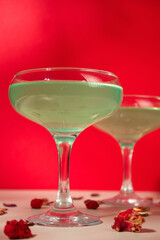 Green cocktail on red background. glass of alcoholic cocktail