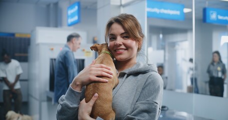 Airport Terminal: Portrait of Happy Woman Holding Her Dog, Smiling, Looking at Camera. In the...