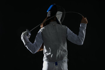 Fencer with epee on black background, back view