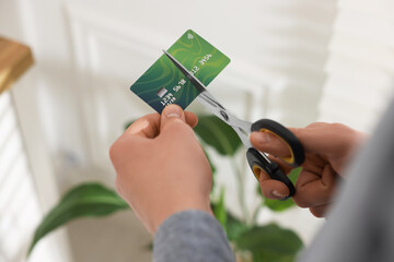 Man cutting his credit card indoors, closeup